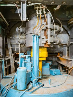 Boruları ve paslı metal yapıları olan terk edilmiş bir fabrikanın içini.