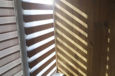 Çalışma masası, jaluzilerde ışık, bilgisayar ve sırt çantası.