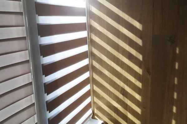 Çalışma masası, jaluzilerde ışık, bilgisayar ve sırt çantası.