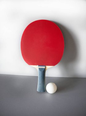 Gri arka planda raket ve ping pong topu.