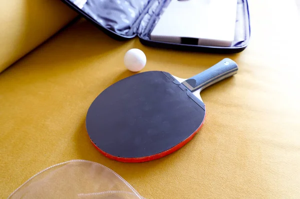 Gri arka planda raket ve ping pong topu.