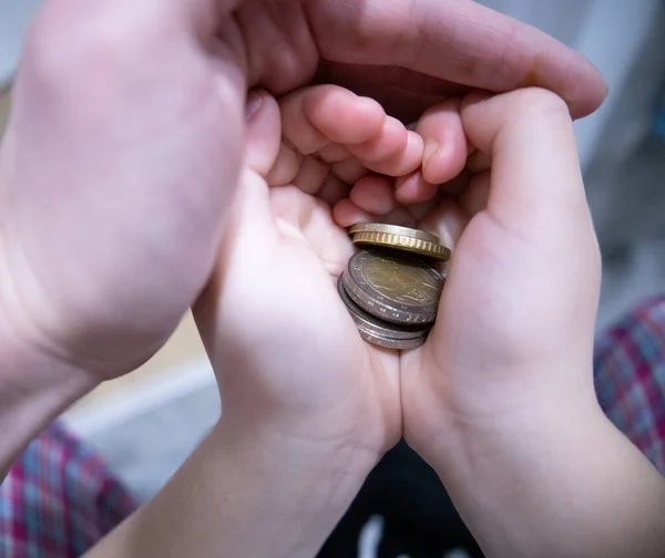 Bebek para ile el ele tutuşur. Ekonomik ve finansal okur yazarlık kavramı. Geleceğe başarılı bir katkı. Bozuk paralarla bir elin yakınlaşması.