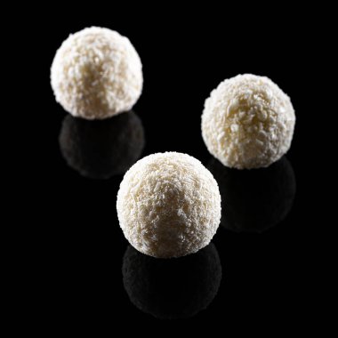Three coconut truffles isolated on black background. Front view. clipart