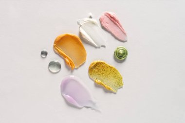 Beyaz arka planda farklı kozmetik lekeler. Yukarıdan görüntüle.