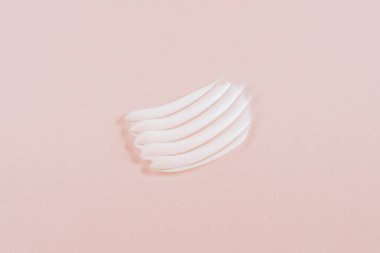 Açık pembe arka planda kozmetik krem ya da serum lekesi. Yukarıdan görüntüle.