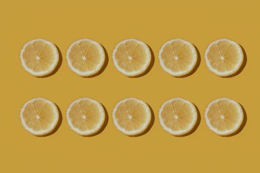Sarı arka planda izole edilmiş dilimlenmiş taze sulu limonlar. Desen