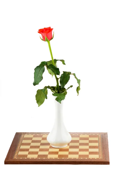 Rose in a vase on a chess board — Stock Photo, Image