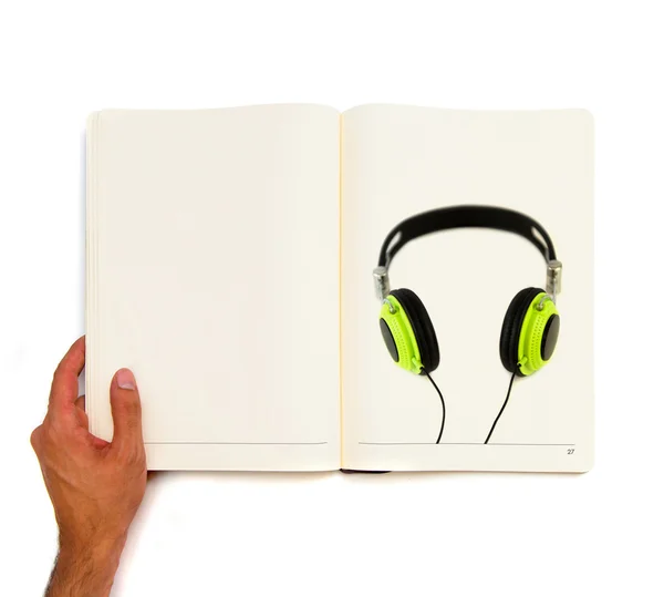 Modern green headphones printed on white book. — Stock Photo, Image