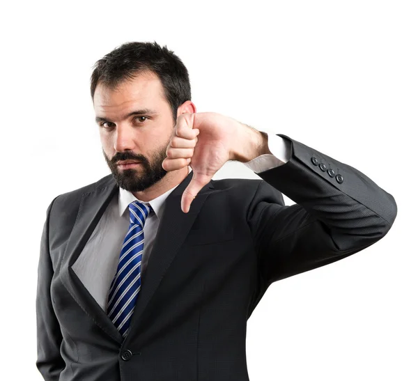 Young businessman with his thumb down over white background — Stock Photo, Image