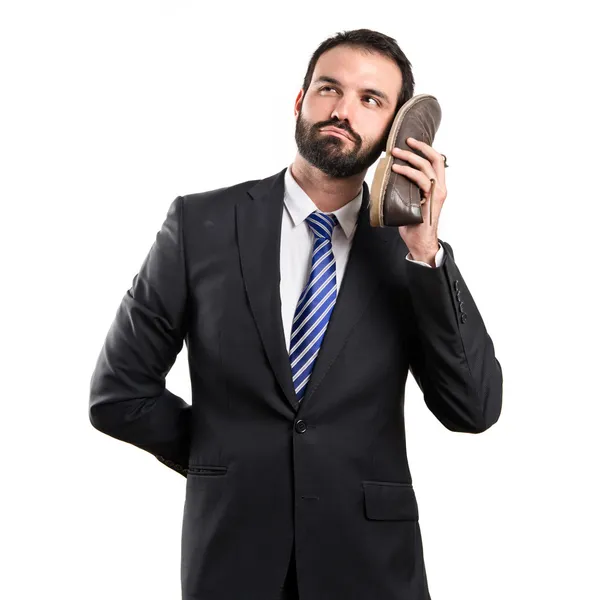 Jovem empresário falando com seu sapato sobre fundo branco — Fotografia de Stock