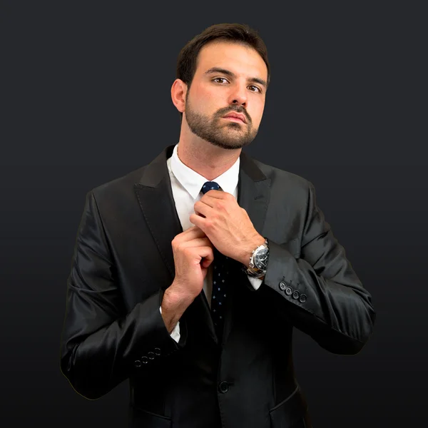 Businessman putting on a necktie over black background — Stock Photo, Image