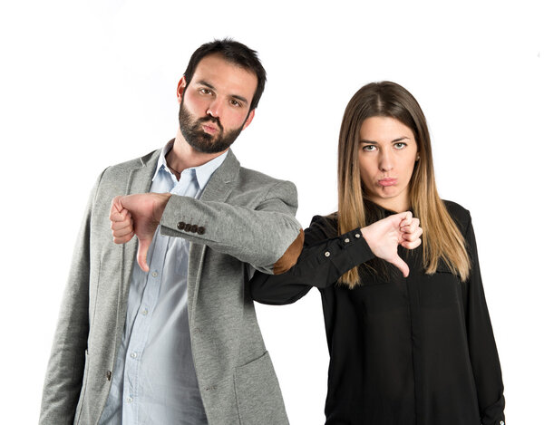 Couple with their thumbs down over white background