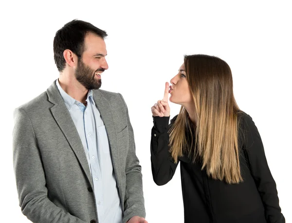 Young girl making silence gesture at her boyfriend over white background — Stock Photo, Image