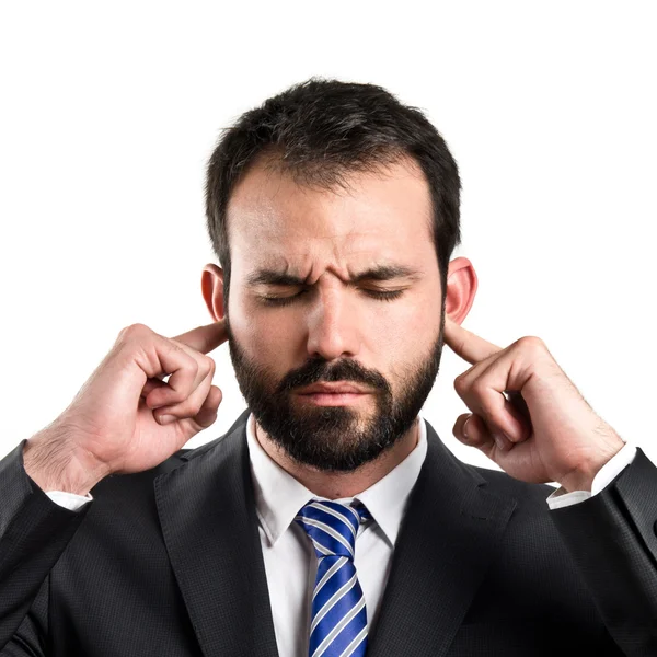 Hombre de negocios cubriendo sus oídos sobre fondo blanco Imágenes de stock libres de derechos