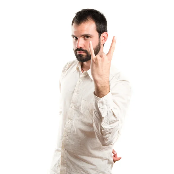 Jeune homme faisant le signe de corne sur fond blanc — Photo