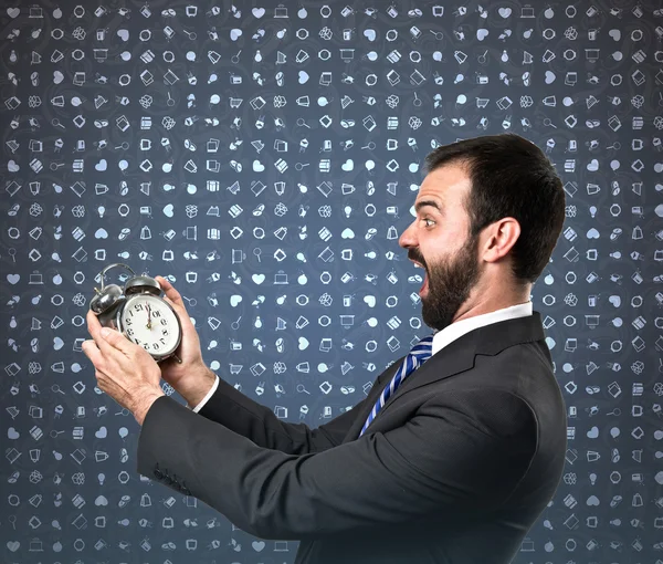 Joven hombre de negocios sosteniendo un reloj antiguo sobre fondo azul —  Fotos de Stock