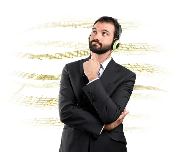 Giovane uomo d'affari ascoltare musica su sfondo bianco — Foto Stock