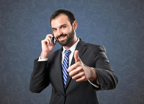 Młodzi biznesmeni rozmowy na telefon komórkowy przez niebieskie tło. — Zdjęcie stockowe