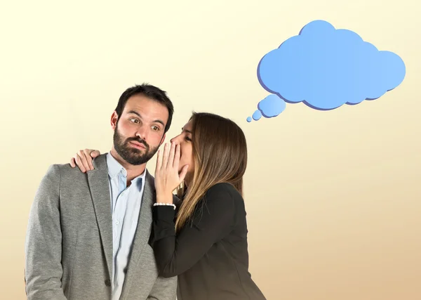 Young girl whispering to her boyfriend over ocher background — Stock Photo, Image