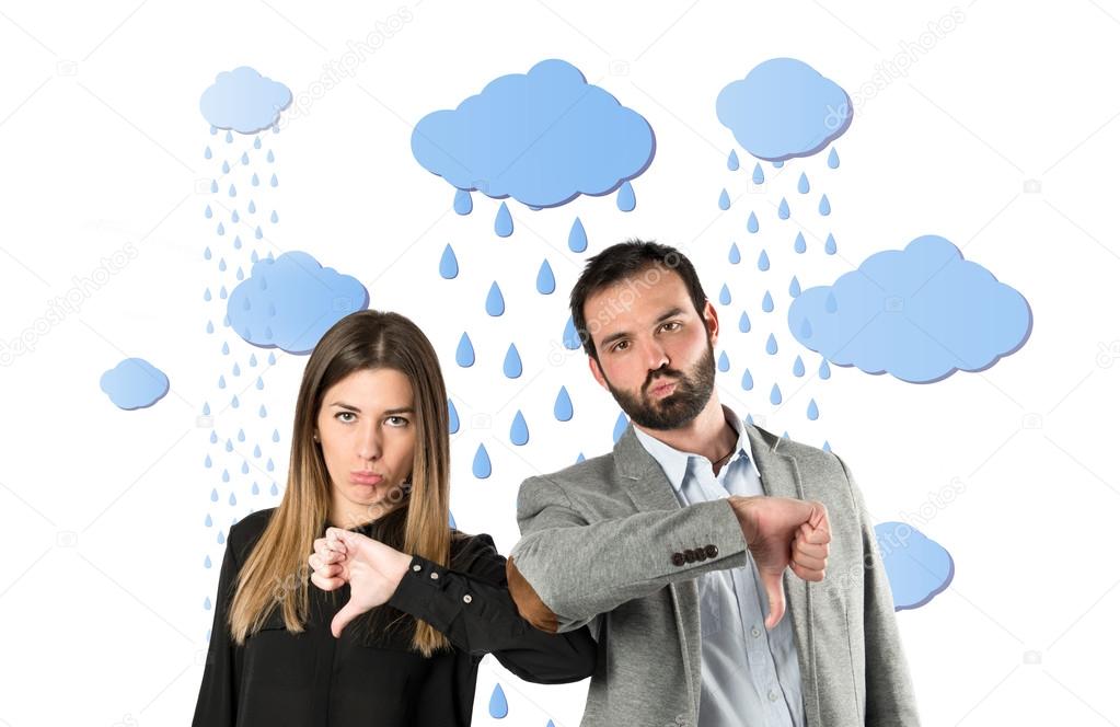 Couple with their thumbs down under the rain