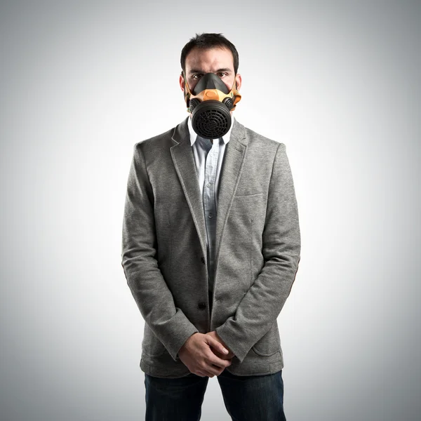 Mladý podnikatel s plynovou masku šedé pozadí — Stock fotografie