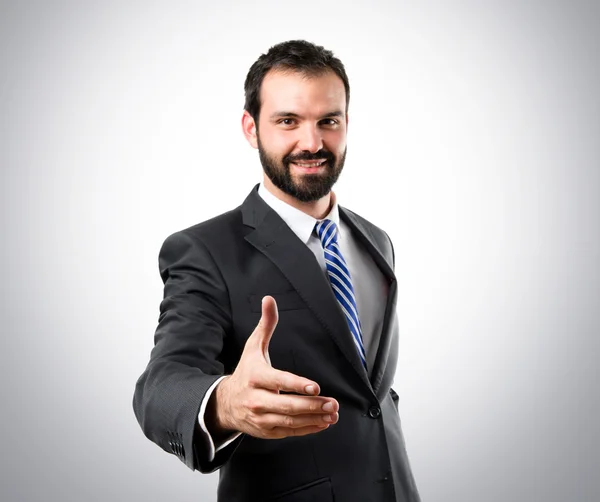 Hombre de negocios haciendo un trato sobre fondo gris — Foto de Stock