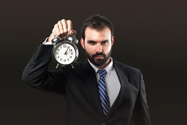 Joven hombre de negocios sosteniendo un reloj antiguo sobre fondo negro —  Fotos de Stock