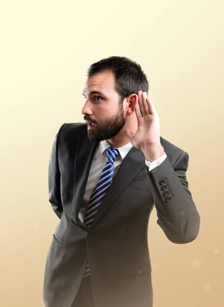 Young business man hearing something over ocher background — Stock Photo, Image