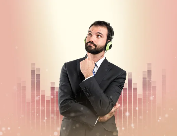 Giovane uomo d'affari ascoltare musica su sfondo fantastico — Foto Stock