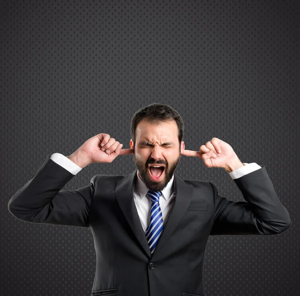 Zakenman die betrekking hebben op haar oren op zwarte achtergrond — Stockfoto