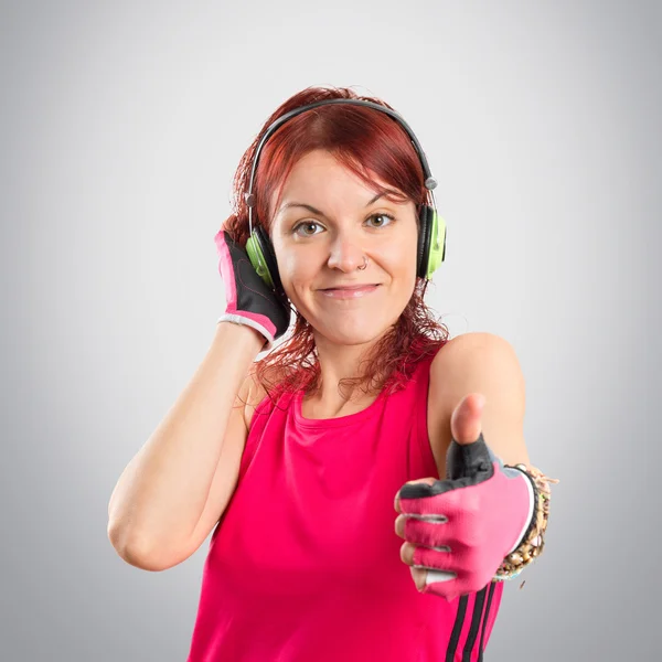 Gri arka plan üzerinde müzik dinleme genç spor kız — Stok fotoğraf