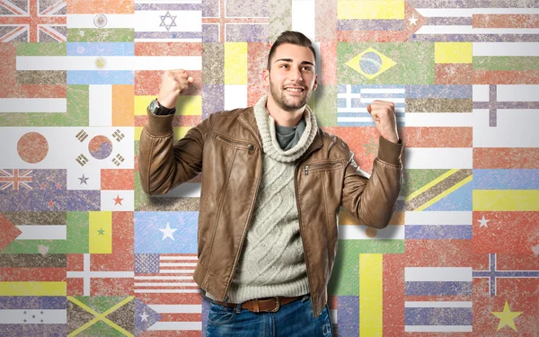 Young man winner over background with flags — Stock Photo, Image