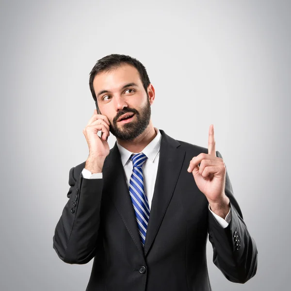 Junge Geschäftsleute sprechen mit Mobiltelefonen vor grauem Hintergrund. — Stockfoto