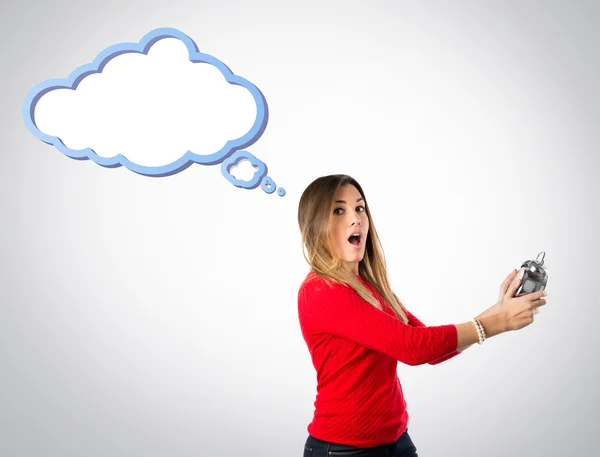 Chica joven sosteniendo un reloj antiguo sobre fondo gris — Foto de Stock