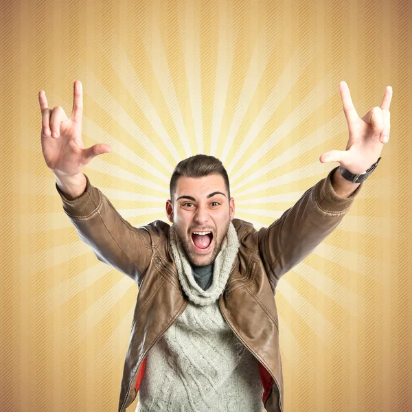 Young man doing the horn sign over yellow background — Stock Photo, Image