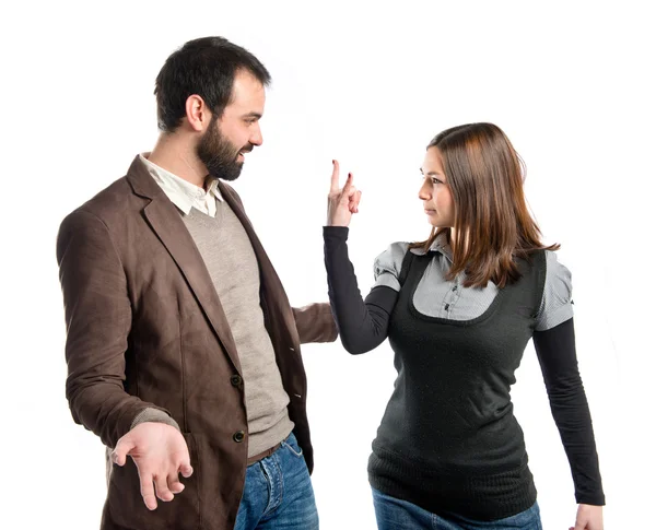 Girl doing the horn sign at her boyfriend over white background — Stock Photo, Image