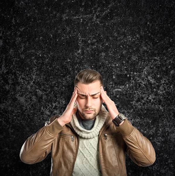 Junger Mann mit Kopfschmerzen über schwarzen strukturierten Hintergrund — Stockfoto