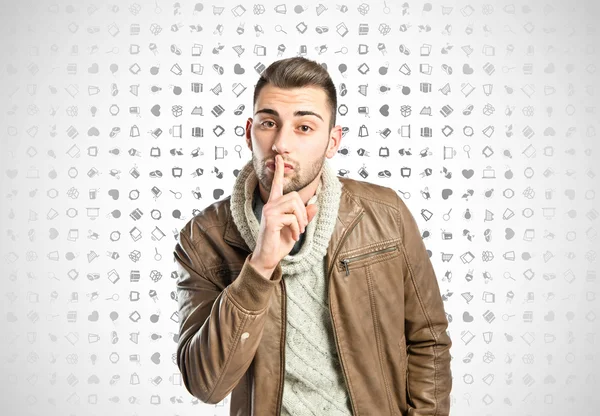 Young man making silence gesture over icons background — Stock Photo, Image