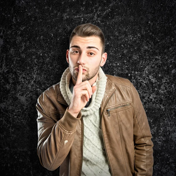 Man making silence gesture over textured black background — Stock Photo, Image