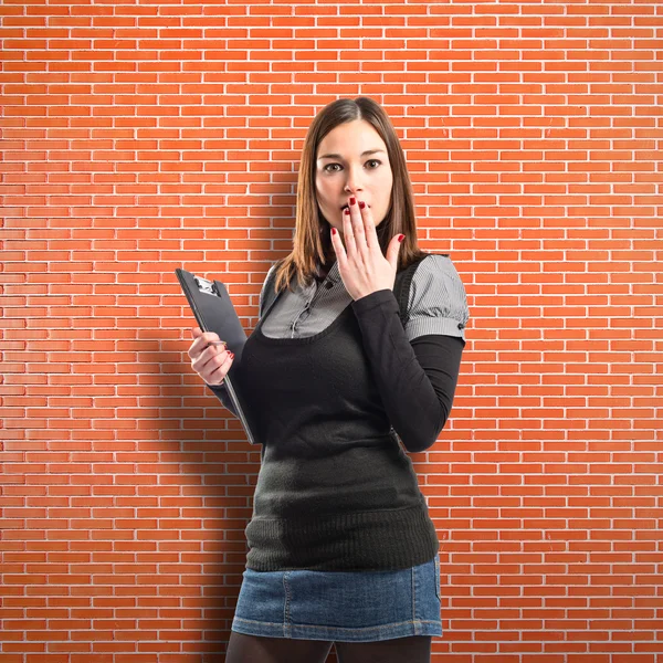 Young student surprised over brick wall background — Stock Photo, Image