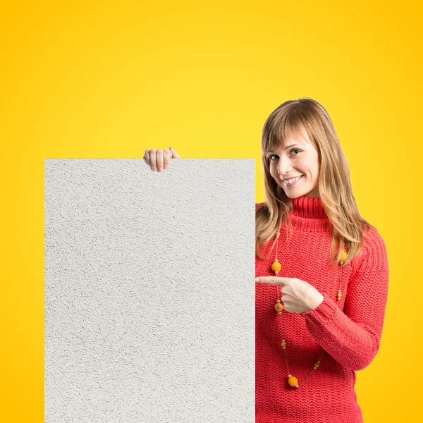 Mladá blondýnka drží texturou cedulky na žlutém pozadí — Stock fotografie