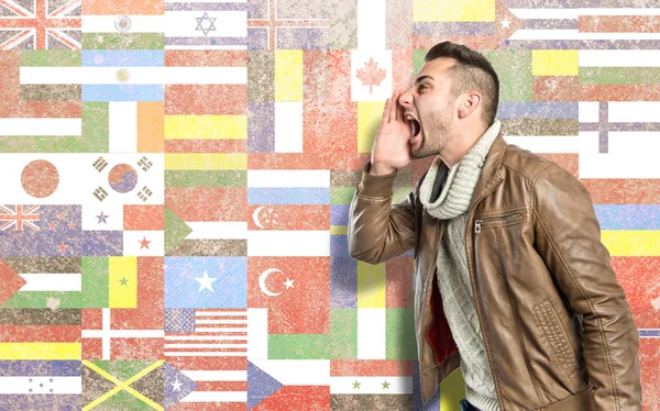 Young man shouting over flags background — Stock Photo, Image