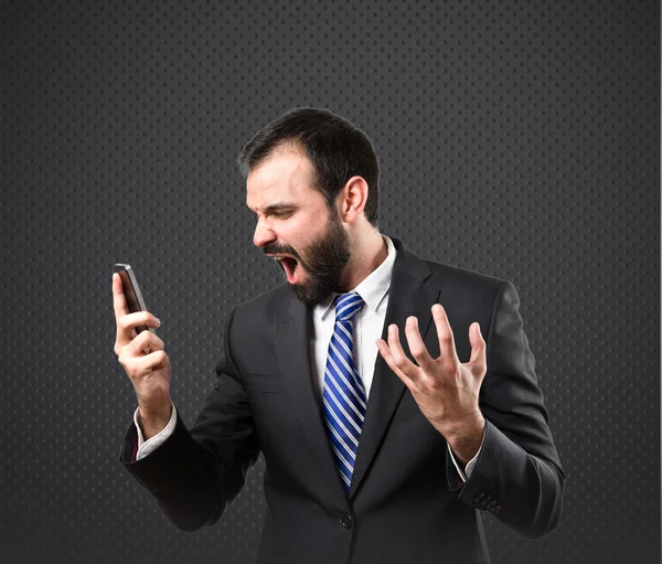 Young businessmen shouting to mobile over black background. — Stock Photo, Image