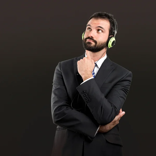 Junger Geschäftsmann hört Musik vor schwarzem Hintergrund — Stockfoto