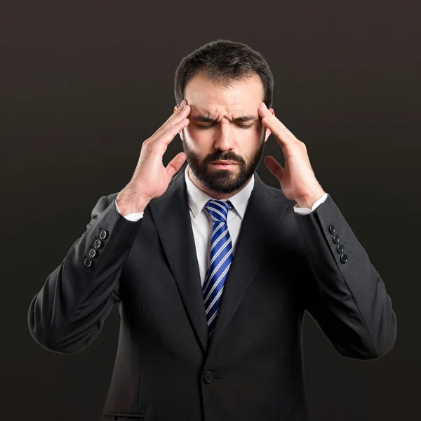 Jonge zakenman met hoofdpijn op zwarte achtergrond — Stockfoto