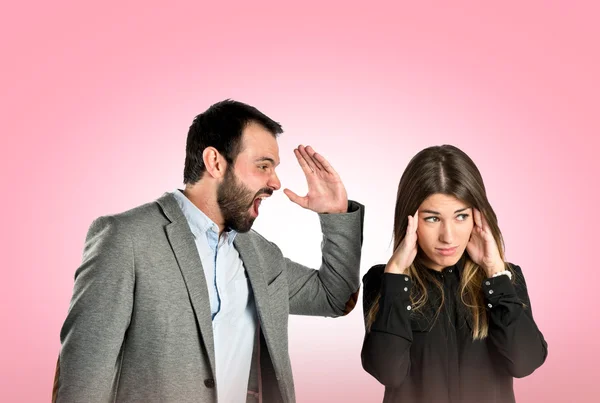 Businessman screaming at his girlfriend over pink background — Stock Photo, Image