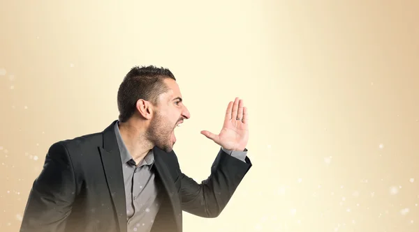 Businessman angry and shouting over ocher background — Stock Photo, Image