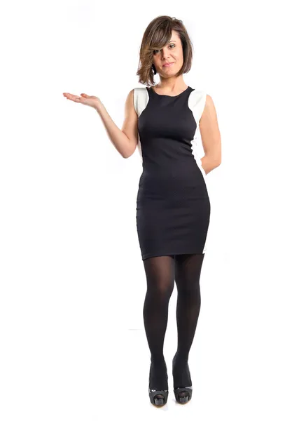 Pretty woman in black dress holding something over white background — Stock Photo, Image