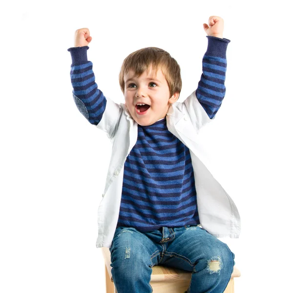 Lucky boy on a wooden chair over white background — Stock Photo, Image