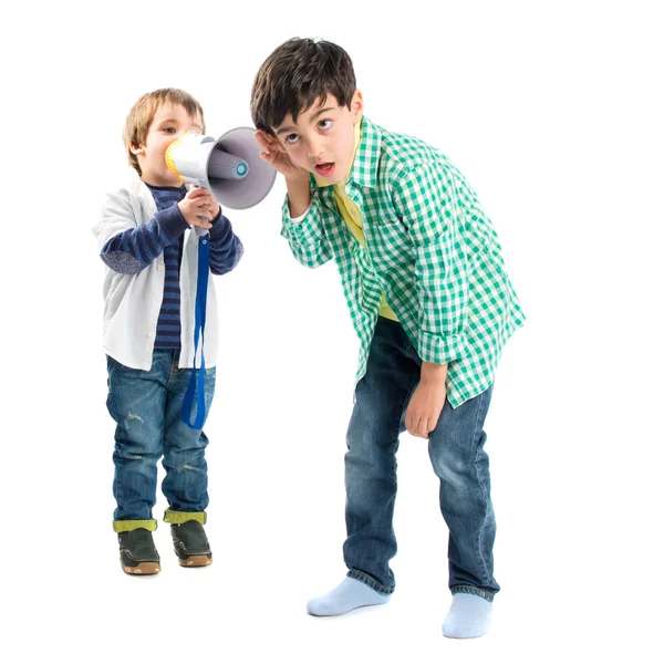 Kid shouting at his friend by megaphone over white background — Stock Photo, Image